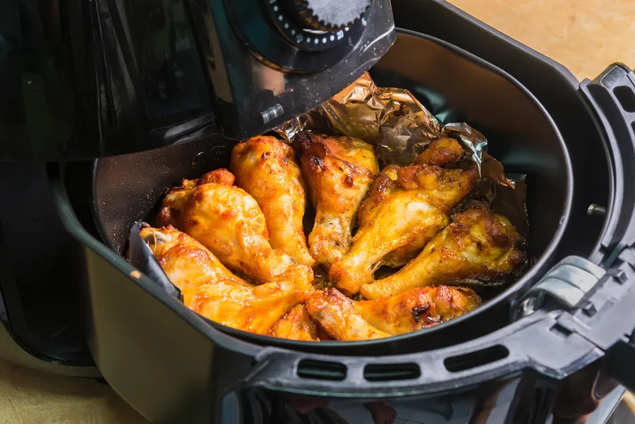 Airfryer, jossa valmistuu herkullisia rapeita kananjalkoja kullanruskeana.